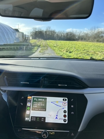 A car dashboard with a screen and a view of a field

Description automatically generated