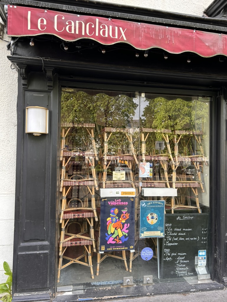 A storefront with a sign and chairs

Description automatically generated